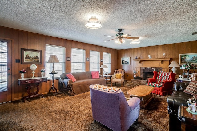 carpeted living room featuring a brick fireplace, ceiling fan, and wooden walls