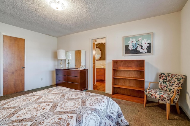 bedroom featuring a spacious closet, carpet floors, ensuite bath, a closet, and a textured ceiling