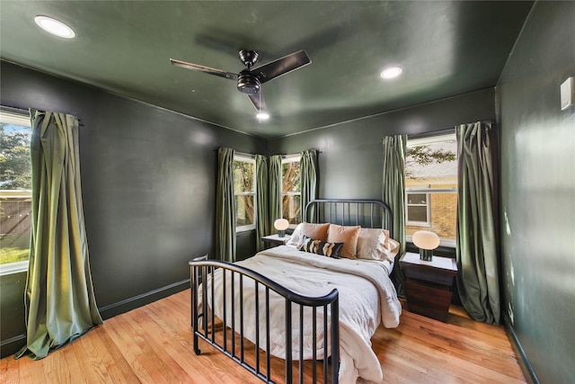 bedroom with ceiling fan, light hardwood / wood-style flooring, and multiple windows