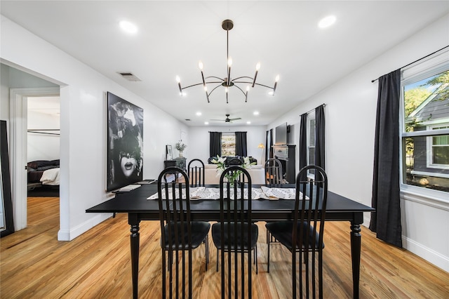 dining room featuring ceiling fan with notable chandelier and light hardwood / wood-style floors