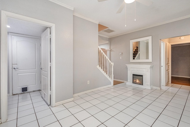 unfurnished living room featuring ceiling fan, crown molding, and light tile patterned flooring