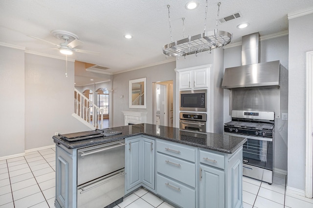 kitchen with white cabinets, wall chimney range hood, stainless steel appliances, and a kitchen island