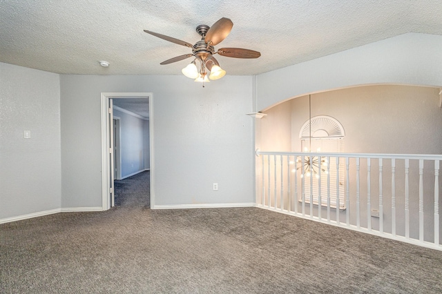 spare room featuring ceiling fan, dark carpet, and a textured ceiling