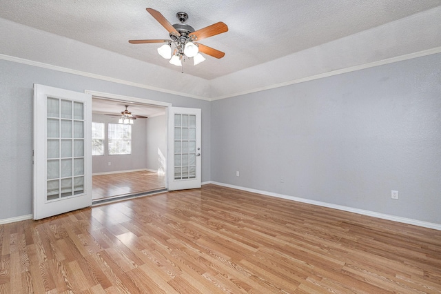 spare room with light wood-type flooring, a textured ceiling, lofted ceiling, and french doors