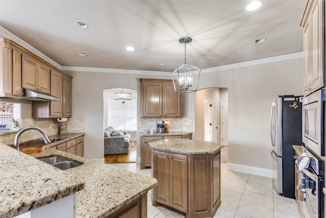 kitchen with pendant lighting, appliances with stainless steel finishes, sink, light stone counters, and a kitchen island