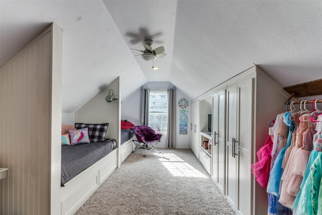 carpeted bedroom with a textured ceiling, vaulted ceiling, and ceiling fan