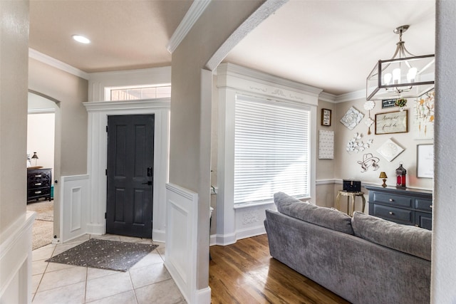 foyer with crown molding, light hardwood / wood-style floors, and a notable chandelier