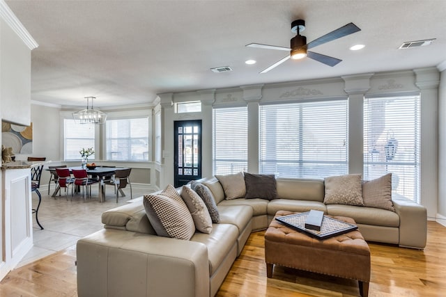 living room with light wood-type flooring, ceiling fan with notable chandelier, and ornamental molding