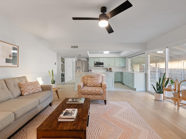 living room with ceiling fan, sink, and light hardwood / wood-style floors