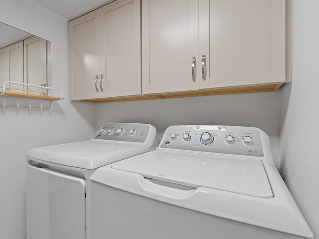 clothes washing area featuring washing machine and dryer and cabinets