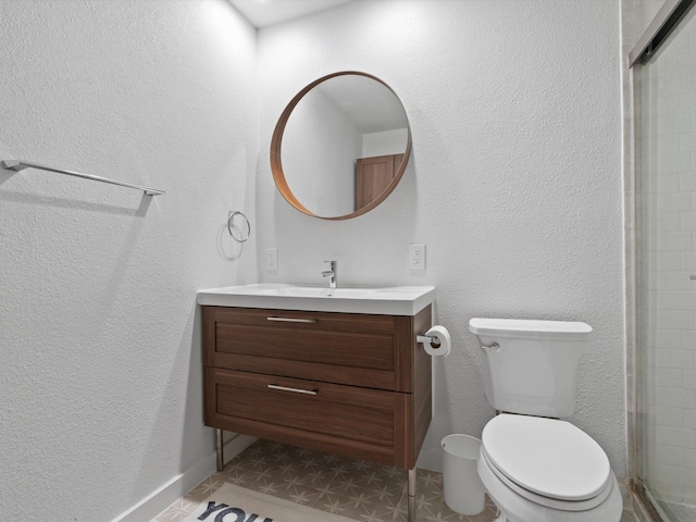 bathroom featuring vanity, a shower with shower door, and toilet