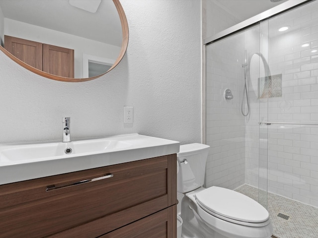 bathroom featuring vanity, a shower with shower door, and toilet