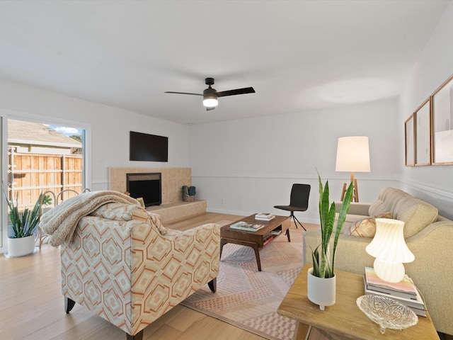 living room featuring ceiling fan, a fireplace, and light wood-type flooring