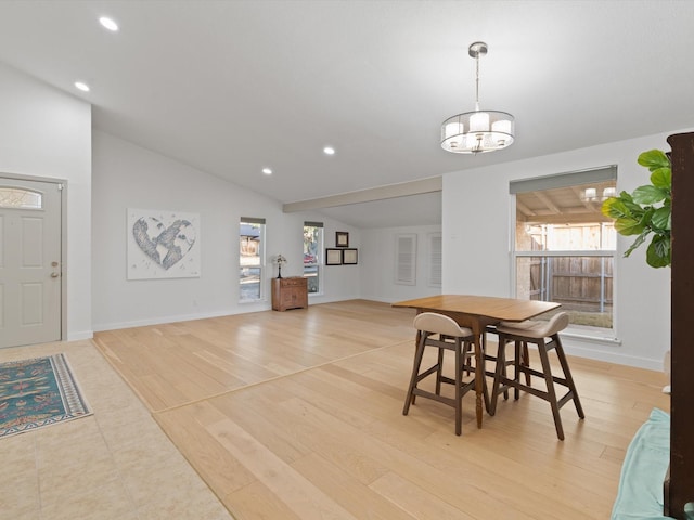 dining area with lofted ceiling, a chandelier, and light hardwood / wood-style floors