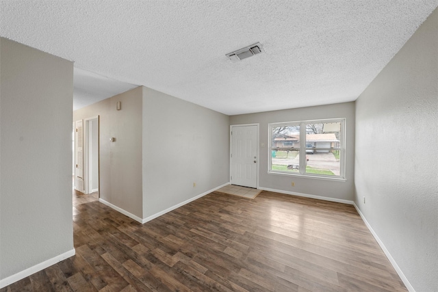 unfurnished room featuring dark hardwood / wood-style flooring and a textured ceiling