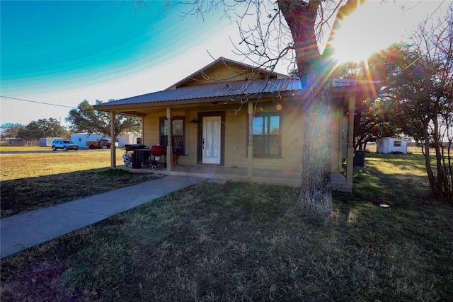 view of front of house with covered porch, a storage unit, and a front lawn