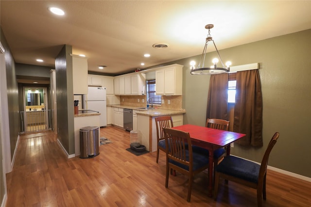 dining space featuring sink, wood-type flooring, and a notable chandelier