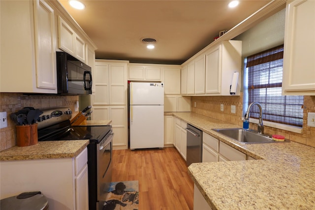 kitchen with appliances with stainless steel finishes, white cabinetry, decorative backsplash, sink, and light hardwood / wood-style flooring