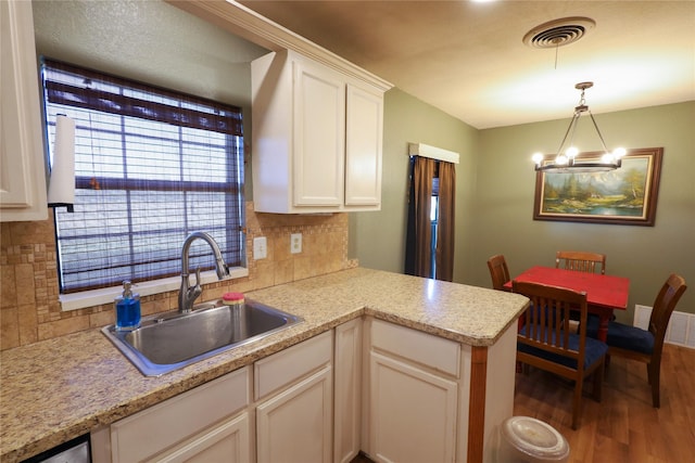 kitchen featuring decorative light fixtures, backsplash, a notable chandelier, sink, and white cabinetry