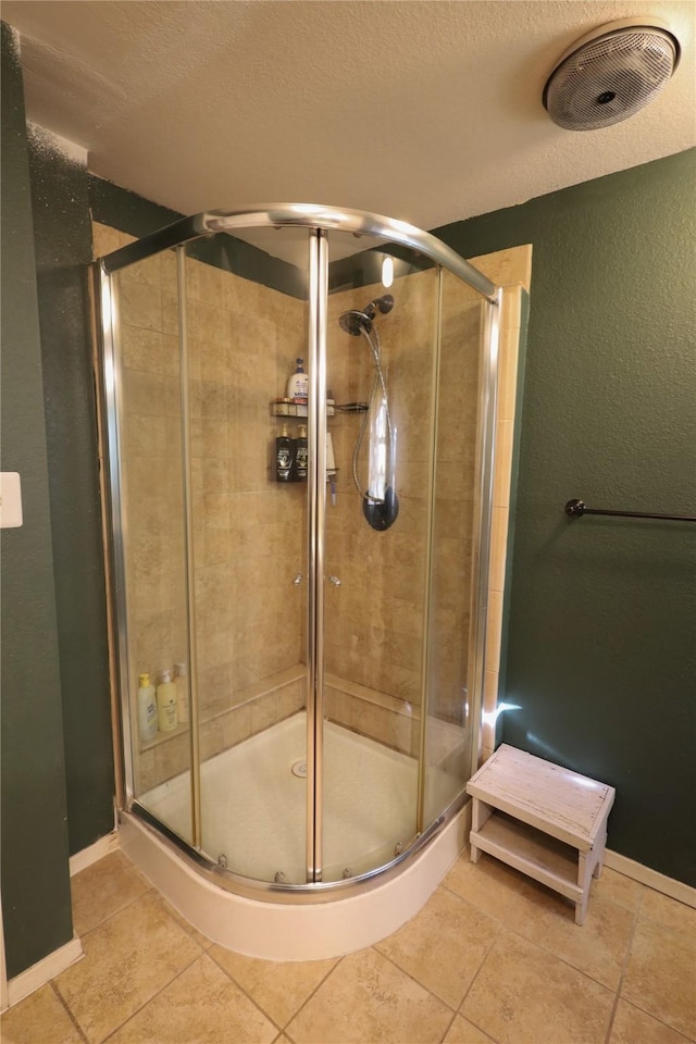 bathroom with a textured ceiling, tile patterned flooring, and a shower with shower door