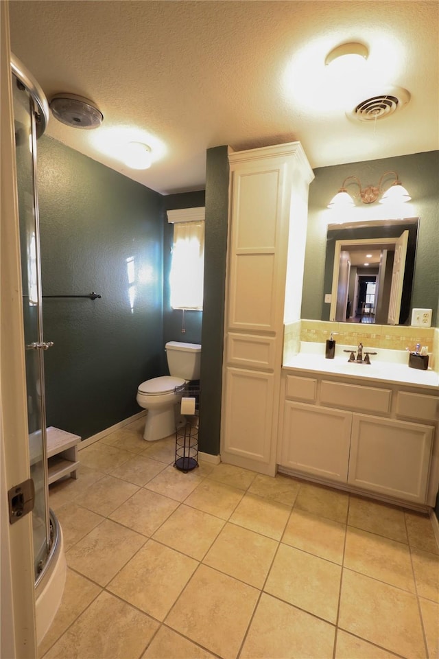 bathroom featuring toilet, tile patterned floors, vanity, and a shower with shower door