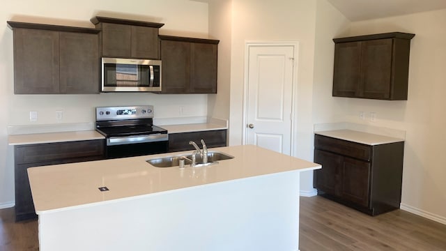 kitchen with stainless steel appliances, dark hardwood / wood-style floors, a kitchen island with sink, dark brown cabinetry, and sink