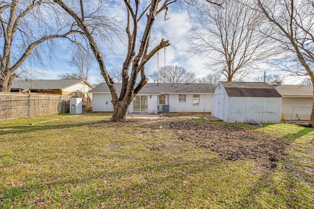 back of property with a lawn, central air condition unit, and a shed