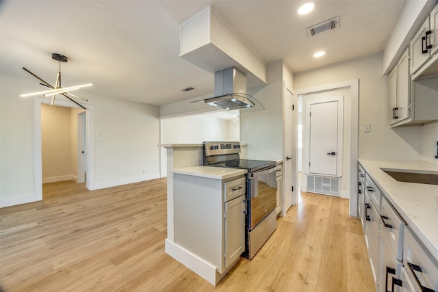 kitchen with stainless steel electric stove, island exhaust hood, an inviting chandelier, light hardwood / wood-style floors, and sink