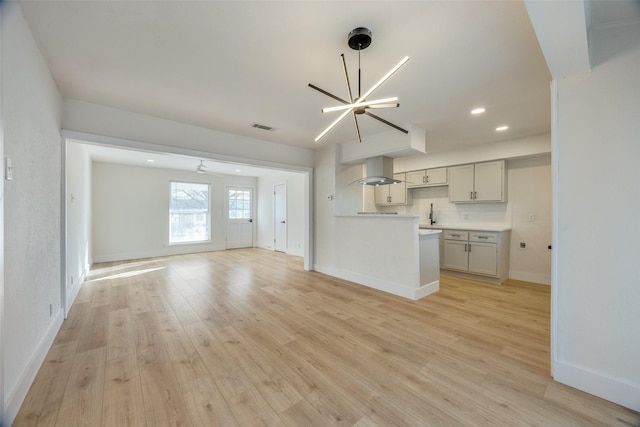 unfurnished living room with a notable chandelier and light hardwood / wood-style flooring