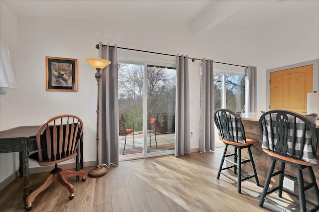 dining area featuring light wood-type flooring and beamed ceiling