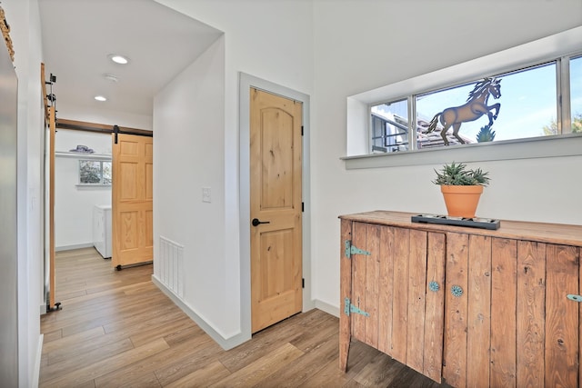 hallway featuring a barn door and light hardwood / wood-style flooring