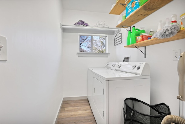 laundry area with washing machine and dryer and light hardwood / wood-style flooring