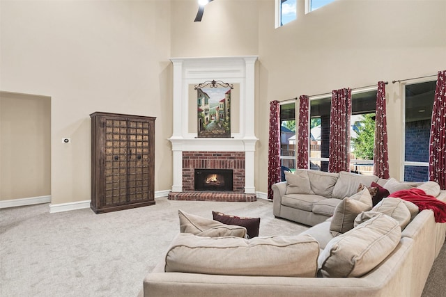 living room with a brick fireplace, a high ceiling, carpet floors, and ceiling fan