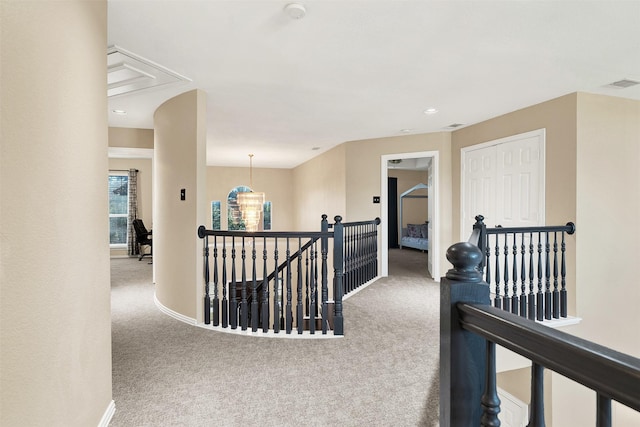 hall featuring carpet floors and a notable chandelier