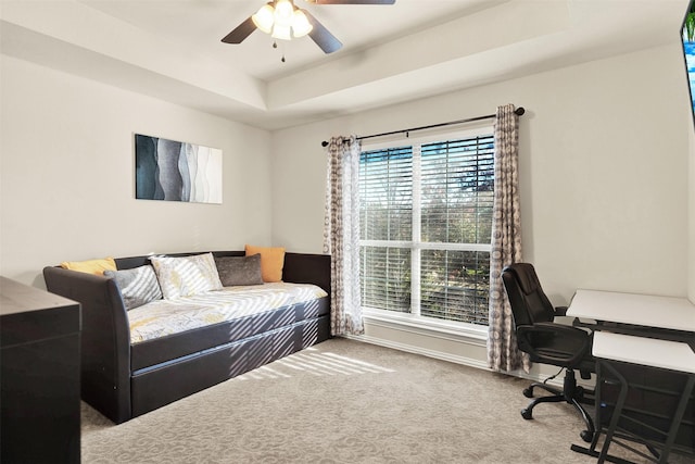 bedroom with ceiling fan, carpet floors, and a raised ceiling