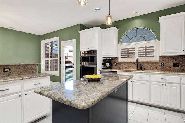 kitchen with white cabinetry, stainless steel double oven, light tile patterned flooring, pendant lighting, and a center island