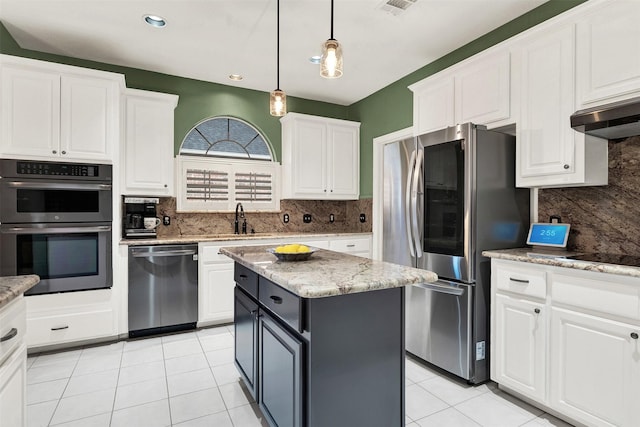 kitchen featuring a kitchen island, light tile patterned floors, light stone countertops, appliances with stainless steel finishes, and white cabinets