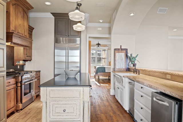 kitchen with white cabinetry, premium appliances, dark hardwood / wood-style floors, ornamental molding, and sink