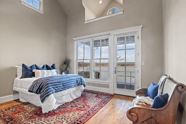 bedroom featuring a towering ceiling, light hardwood / wood-style flooring, and access to outside