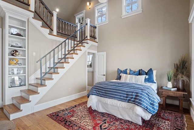 bedroom with a towering ceiling and wood-type flooring