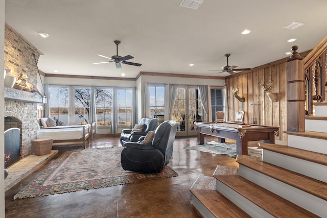 living room featuring ceiling fan, crown molding, french doors, and wooden walls