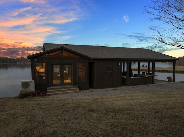 view of front of property featuring a water view, a yard, and ac unit