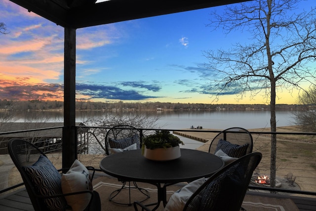 deck at dusk featuring a water view