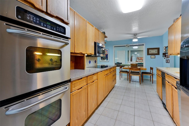 kitchen featuring a textured ceiling, light tile patterned floors, appliances with stainless steel finishes, and light stone countertops