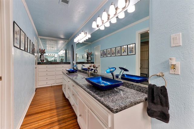 bathroom featuring hardwood / wood-style floors, vanity, ornamental molding, and a textured ceiling