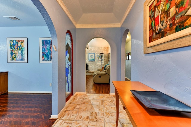 hall featuring a textured ceiling, ornamental molding, and lofted ceiling