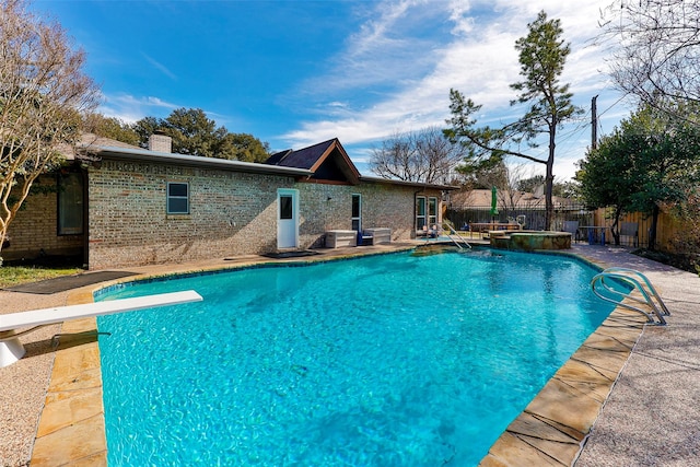 view of pool featuring a hot tub, a diving board, and a patio