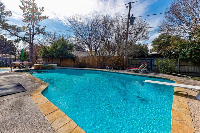 view of swimming pool with a diving board, a patio area, and a hot tub