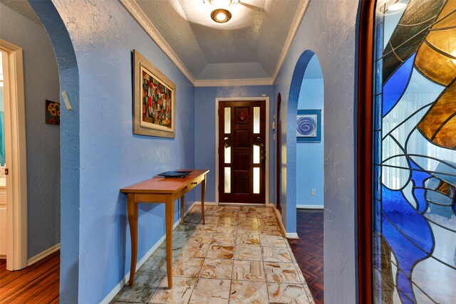 entryway with parquet flooring, a tray ceiling, lofted ceiling, a textured ceiling, and ornamental molding