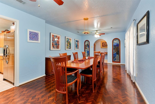 dining space featuring ceiling fan, dark parquet floors, and a textured ceiling